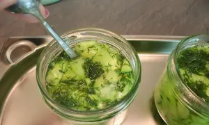Ein Glas Gurkensalat mit Dill wird mit einem Löffel vorbereitet, bereit zum Gurkensalat einkochen.