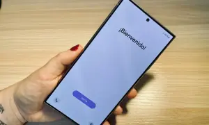 Mano sujetando un móvil listo para formatear. Pantalla de bienvenida con el botón "Inicio" visible.