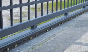 Metalowa listwa zębata do bramy przesuwnej, z widocznymi ząbkami i rolkami prowadzącymi.