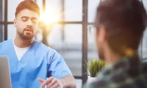 Lekarz w niebieskiej koszuli rozmawia z pacjentem. Czy trzeba mieć skierowanie do psychiatry? Zapytaj lekarza.