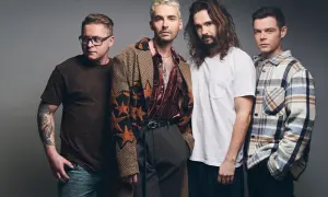 Tokio Hotel Polska: czterech mężczyzn w stylowych strojach pozuje do zdjęcia. Jeden z nich ma tatuaż na ramieniu.