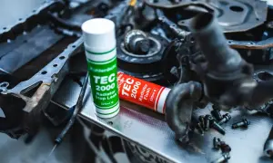 Uszkodzony cylinder objawy? Na stole leżą części silnika i dwa preparaty TEC 2000: Radiator Stop Leak i Radiator Flush.