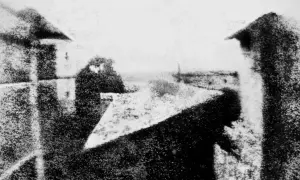 Immagini bianco e nero di un paesaggio urbano con edifici e cielo. La prospettiva è dall'alto, con un tetto in primo piano.