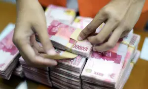 Ręce liczą stosy banknotów 100 000 rupii, waluta Indonezji.