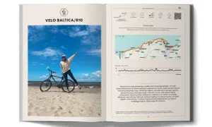 Rowerzystka na plaży z rowerem, obok mapa trasy Velo Baltica/R10. To nie są trasy rowerowe Słowacja, lecz polskie wybrzeże Bałtyku.
