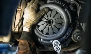 Mechanik w rękawicy próbuje zamontować tarczę sprzęgła. Ciezko wchodzi 1, ale z kluczem nasadowym praca pójdzie sprawniej.