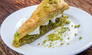 Pyszne ciasto na baklawę z pistacjami i kremem, podane na białym talerzu.