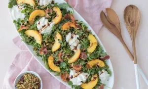 Salade d'été avec pêche, burrata crémeuse, roquette, prosciutto croustillant et vinaigre balsamique. Un délice !