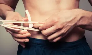 Uomo con plicometro misura il grasso corporeo, un dettaglio per capire il significato di ectomorfo e la sua costituzione fisica.