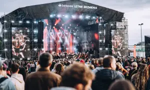 Koncert Santander Letnie Brzmienia z orkiestrą na żywo i ekranami pokazującymi muzyków. Tłum widzów czeka na występ.