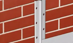 Metalowe listwy do tynkowania przykręcone do ceglanej ściany, tworzące narożnik.