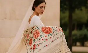 Novia con velo y mantón bordado con flores, mostrando elegantes formas de poner un mantón.
