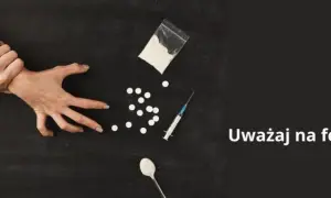 Dwie ręce walczą o kontrolę nad przedmiotami związanymi z narkotykami, w tym proszkiem, tabletkami i strzykawką. Uważaj na fentanyl.