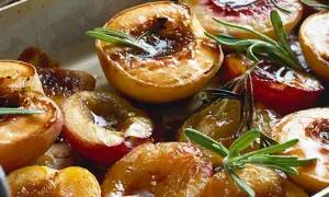 Halverade, karamelliserade persikor med rosmarin i en ugnsform. En härlig grillad persika som ser otroligt god ut.