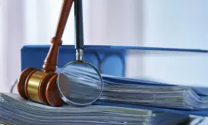 Martelletto da giudice e lente d'ingrandimento su fascicoli: un invito a capire perchè studiare giurisprudenza, analizzando le leggi.