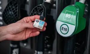 Dłoń trzyma dodatek do paliwa E10, obok dystrybutora z oznaczeniem 95. Idealny dla klasyków jak Fiat X1/9.