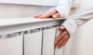 Dłonie sprawdzają ciepło grzejnika, przygotowując się na nadchodzący sezon grzewczy.
