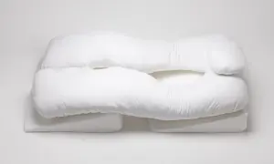 A white, U-shaped body pillow, designed for comfort and support, rests on wedge-shaped cushions. These almohadas ortopédicas offer a cozy embrace.