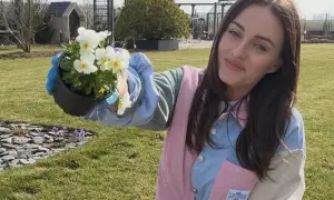 Uśmiechnięta Ania Bardowska, która ma 30 lat, sadzi kwiaty w ogrodzie.