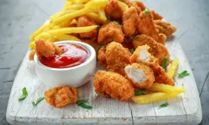 Chrupiące nuggetsy w płatkach kukurydzianych, podane z frytkami i ketchupem. Idealna przekąska na każdą okazję.