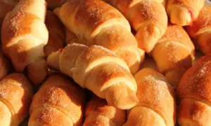 Złociste rogaliki drożdżowe posypane cukrem, niektóre z nadzieniem. Idealne na śniadanie.