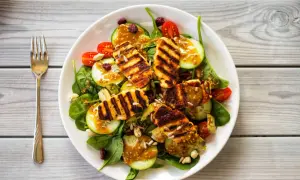 Pyszna sałatka z grillowanym halloumi, świeżym ogórkiem, pomidorkami i chrupiącymi nasionami słonecznika, polana sosem musztardowym.
