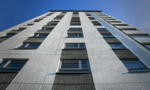 Facciata di un palazzo con file di finestre, sotto un cielo blu. Potrebbe rappresentare il punteggio minimo per casa popolare.