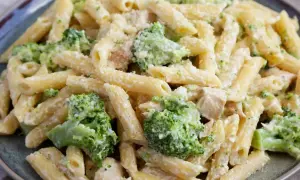Makaron penne z brokułami i kurczakiem w kremowym sosie na talerzu.