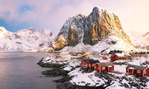Village de pêcheurs aux maisons rouges sur pilotis, sous des montagnes enneigées. Un paysage typique de la Norvège.