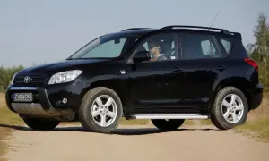 Czarny, mały SUV dla kobiety, zaparkowany na piaszczystej drodze. Kierowca w okularach siedzi za kierownicą.