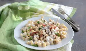 Piatto di pasta alla boscaiola cremosa con funghi e pancetta, guarnita con prezzemolo fresco.
