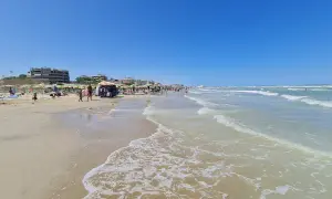 Spiaggia affollata a Senigallia mare, con ombrelloni, lettini, bancarelle e gente che passeggia. Il mare azzurro e calmo invita a un tuffo.