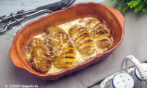 Gerichte mit Kartoffeln: Hasselback-Kartoffeln in cremiger Sauce, goldbraun gebacken und mit Käse überbacken, serviert in einer Auflaufform.