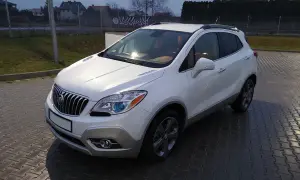Biały Buick Encore stoi na mokrej, brukowanej nawierzchni.