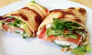 Zwei herzhafte Pfannkuchen gefüllt mit Salat, Tomaten und Käse auf einem weißen Teller.