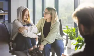 Wsparcie w trudnych chwilach: psychoterapia dla młodzieży. Dwie dziewczyny siedzą obok siebie, jedna z nich szuka pocieszenia.