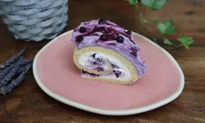 Roulé moelleux garni de crème chantilly mascarpone et myrtilles, nappé d'une crème violette aux fruits.