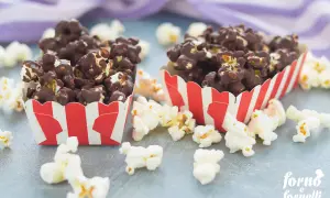Due contenitori a righe rosse e bianche pieni di pop corn al cioccolato, perfetti per scoprire come fare i pop corn al cioccolato.