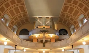 Orgel und Kruzifix im St. Pauli Dom. Die geschwungene Empore und die kunstvolle Deckenkonstruktion schaffen eine feierliche Atmosphäre.