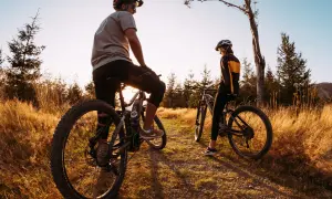Dwie osoby na rowerach górskich odpoczywają na ścieżce wśród traw. Idealne miejsce na odkrywanie tras rowerowych Śląsk.
