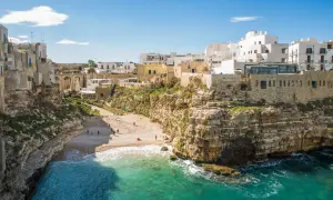 Un'idea per il tuo itinerario Puglia 7 giorni in macchina: la costa rocciosa di Polignano a Mare con la sua spiaggia e le case bianche a picco sul mare.
