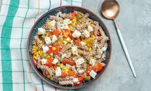 Insalata di pasta integrale con pomodorini, mais, olive e feta. Un condimento pasta per dieta leggero e gustoso.