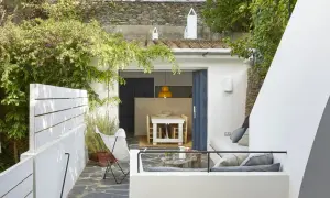 Un moderno patio andaluz con muebles blancos, vegetación exuberante y un rincón acogedor para relajarse.