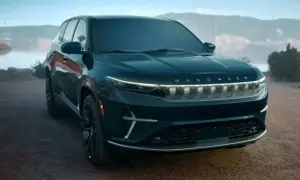 Elegancki, ciemnogranatowy Jeep Wagoneer z podświetlanym napisem na grillu, zaparkowany na tle malowniczego krajobrazu z jeziorem i górami.