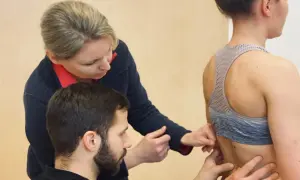 Fizjoterapeuci badają kręgosłup pacjentki.