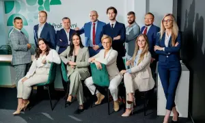 Zespół prawników w garniturach pozuje do zdjęcia w nowoczesnym biurze.