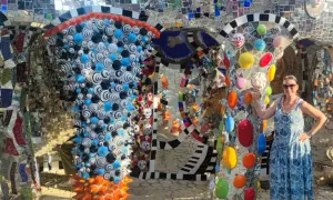 Donna sorride nel Giardino dei Tarocchi, un luogo magico pieno di mosaici colorati e sculture bizzarre.