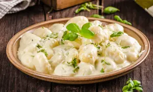 Pyszne gnocchi z kurczakiem w kremowym sosie, posypane parmezanem i świeżą bazylią. Idealne danie na obiad.