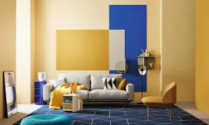 Modernes Wohnzimmer mit gelber Wandkunst, die die Farbe Gelb und ihre Bedeutung von Freude und Optimismus hervorhebt. Ein graues Sofa, ein blauer Teppich und ein gelber Sessel.