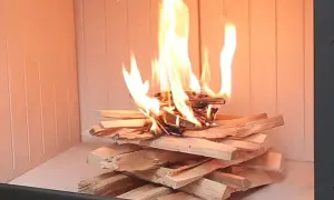 Płonące drewno w kominku, na tle jasnego szamotu. Ciepło rozchodzi się po wnętrzu.